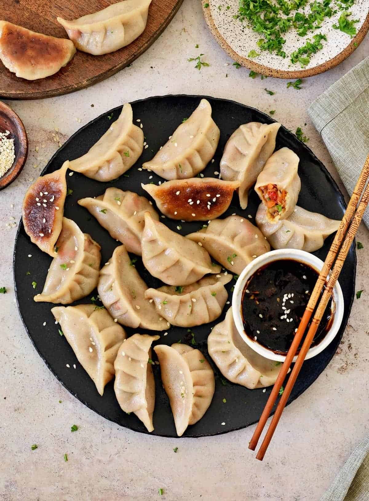 vegan vegetable dumplings on black plate with sauce