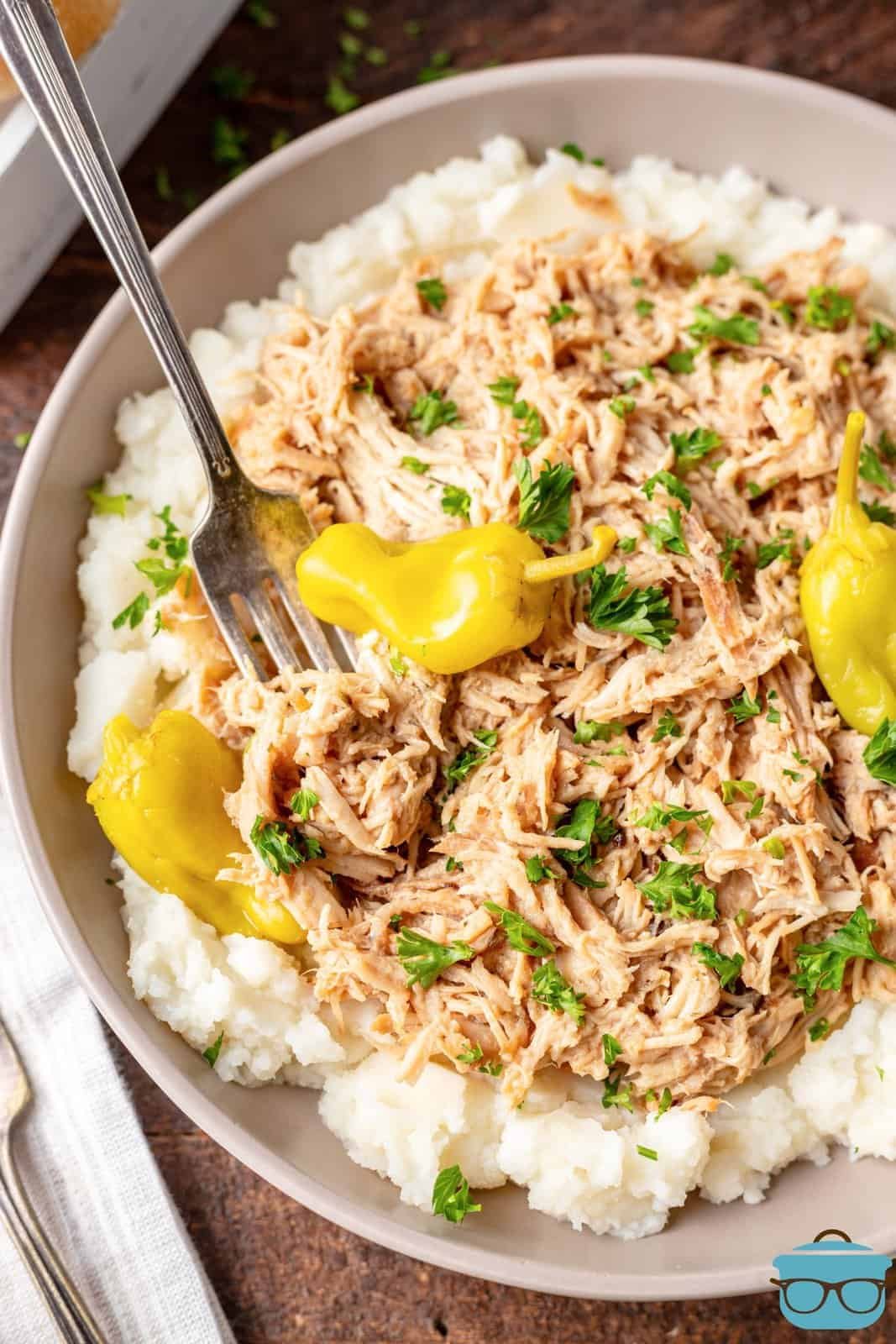 Crockpot Mississippi Chicken shown on mashed potatoes in a white bowl scaled 1